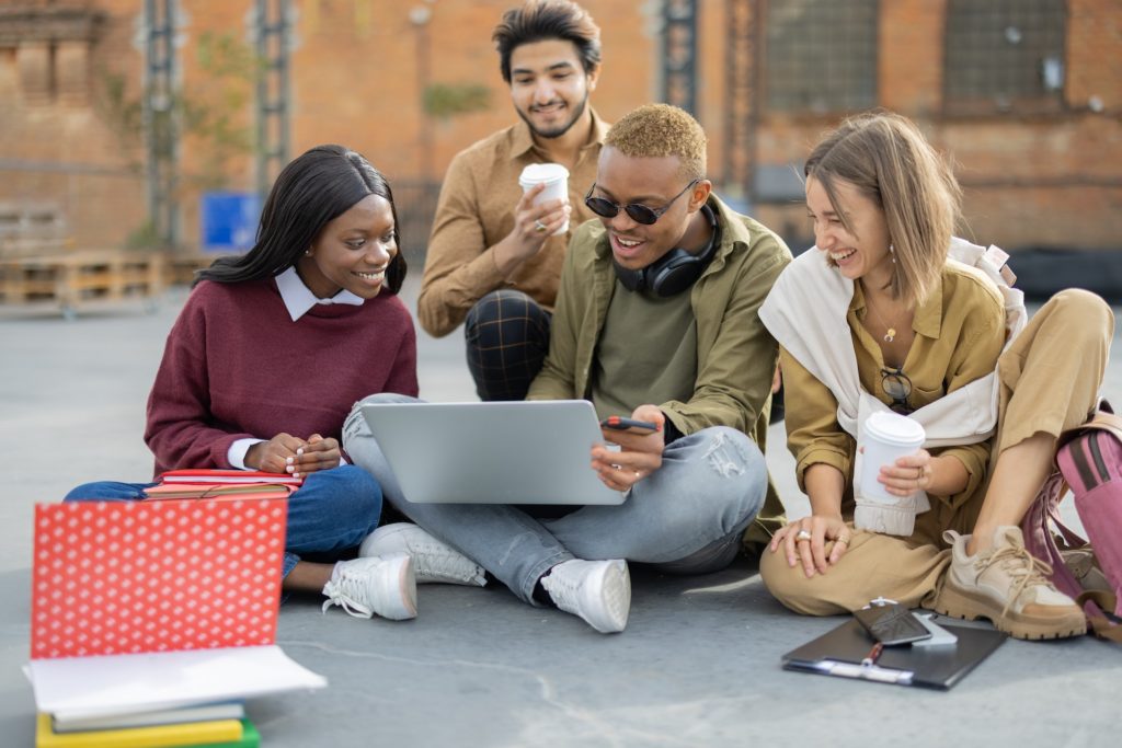 Students watching something on laptop on asphalt
